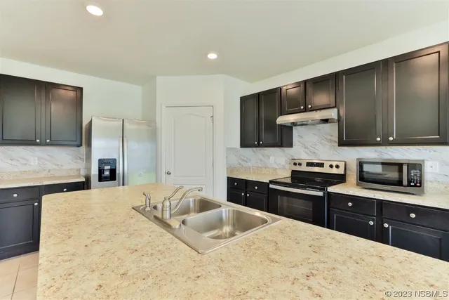 a kitchen with stainless steel appliances granite countertop a sink a stove and a refrigerator