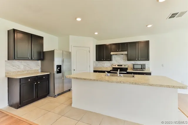 a kitchen with stainless steel appliances granite countertop a stove a sink and a microwave