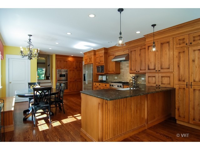 187 Ridge Avenue Winnetka, IL 60093 - Photo 3 of 18 a kitchen with stainless steel appliances kitchen island granite countertop a stove a refrigerator a sink a dining table and chairs with wooden floor