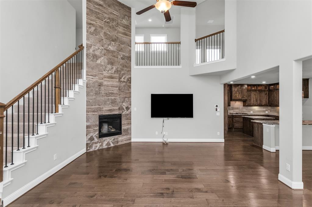 6333 Hall Road Frisco, TX 75034 - Photo 8 of 38 Two-story living area featuring wood-finish flooring, a stone-clad fireplace, and a ceiling fan