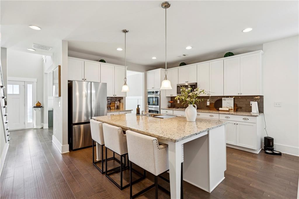 4006 Glendianne Way Powder Springs, GA 30127 - Photo 5 of 21 a kitchen with stainless steel appliances granite countertop a table chairs refrigerator and microwave