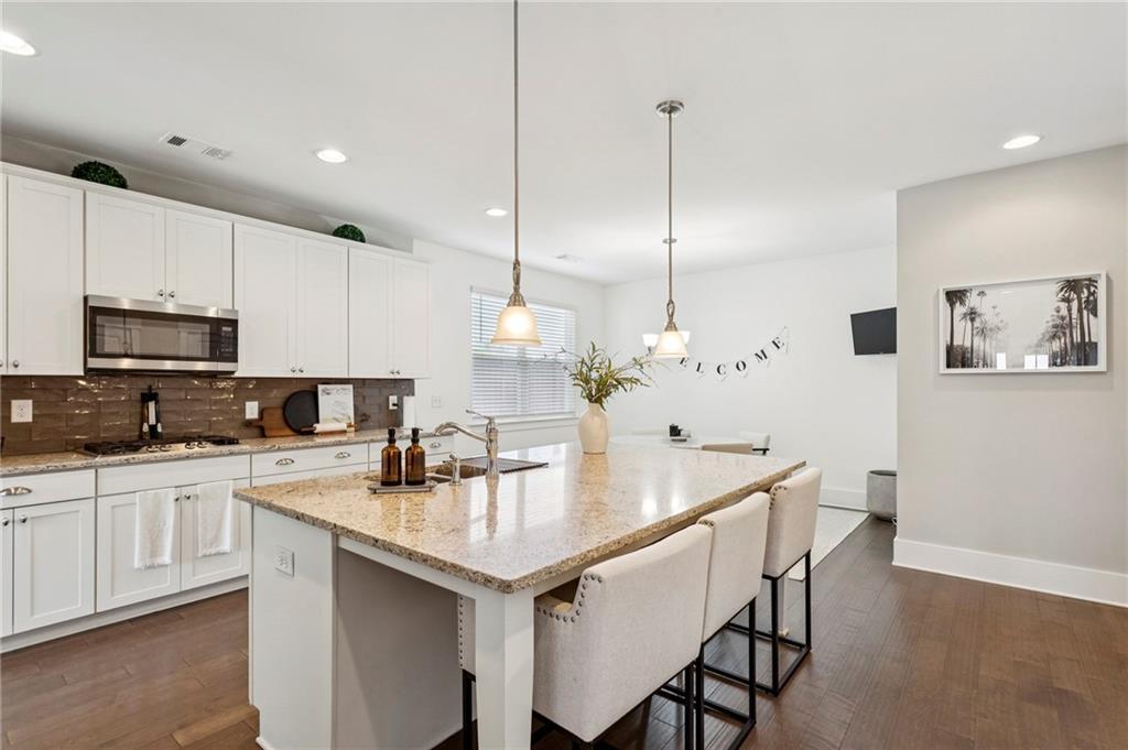 4006 Glendianne Way Powder Springs, GA 30127 - Photo 6 of 21 a kitchen with stainless steel appliances granite countertop a sink a stove a refrigerator and white cabinets with wooden floor