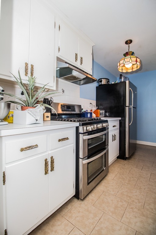14 Governors Street Worcester, MA 01606 - Photo 12 of 26 a kitchen with stainless steel appliances a stove a chimney and cabinets
