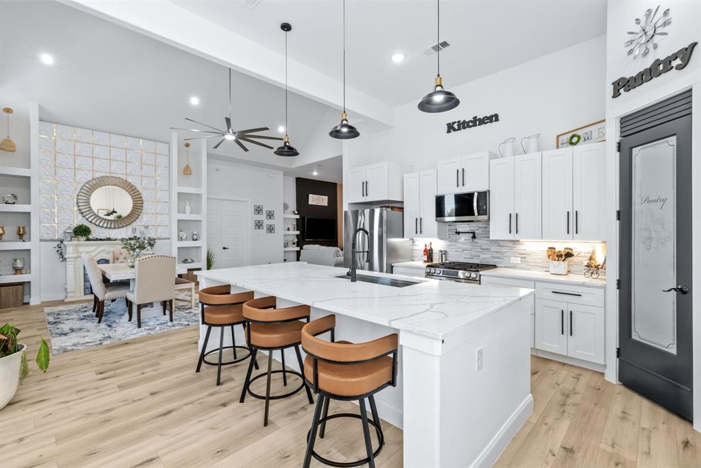 971 Sister Grove Road Van Alstyne, TX 75495 - Photo 4 of 38 a kitchen with stainless steel appliances kitchen island granite countertop a stove a sink a dining table and chairs with wooden floor