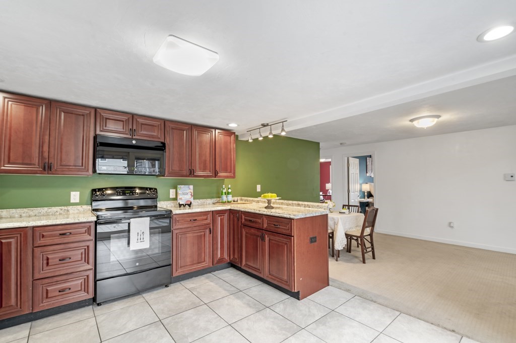 26 Temple Drive Methuen, MA 01844 - Photo 13 of 38 a kitchen with a stove a sink a microwave and wooden cabinets