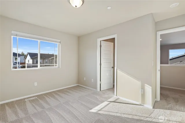 a view of an empty room with wooden floor and kitchen