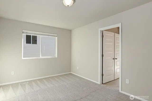 a view of an empty room with closet and a window