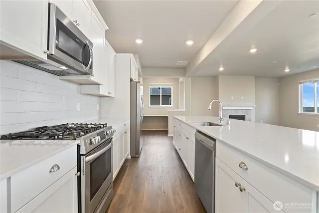 a large kitchen with stainless steel appliances granite countertop a lot of counter space and wooden floors