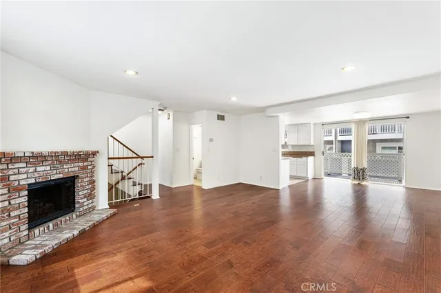 a view of an empty room with wooden floor and a fireplace