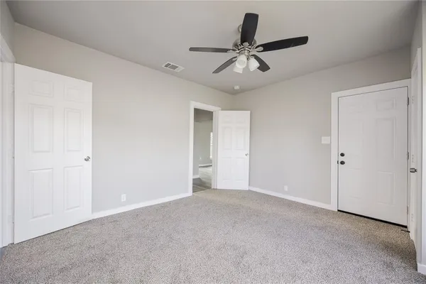 a view of an empty room and chandelier fan