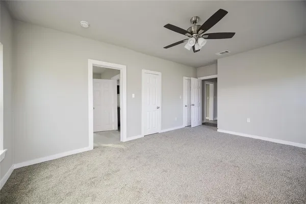 an empty room with closet and ceiling fan