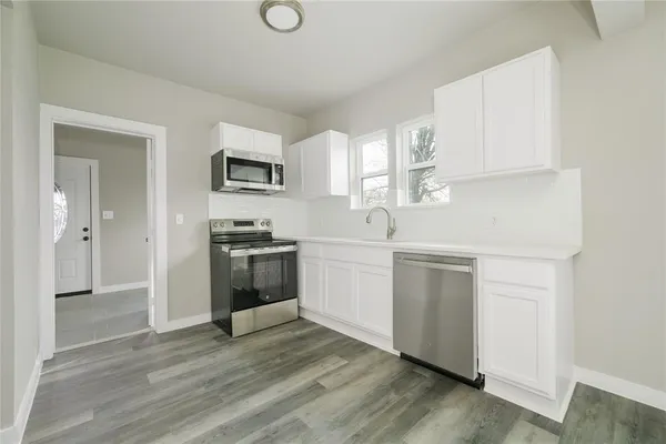 a kitchen with white cabinets and stainless steel appliances