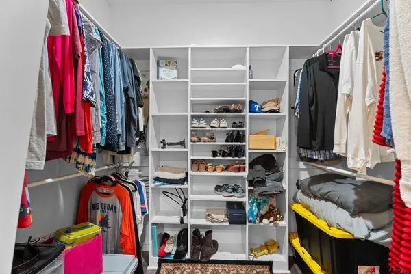 a view of walk in closet with clothes and shoes