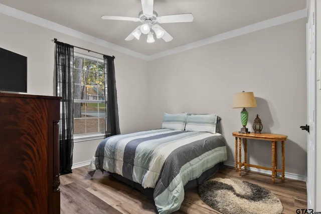 a bedroom with a bed table and two window