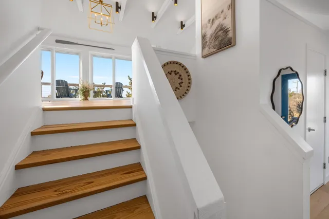 a view of staircase with lots of frames on wall and a window