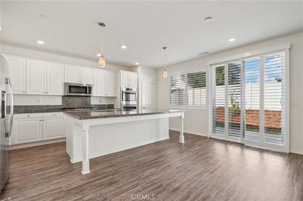 29594 Chelton Way Menifee, CA 92584 - Photo 14 of 48 a kitchen with stainless steel appliances granite countertop a stove a sink a refrigerator white cabinets and wooden floor next to a window