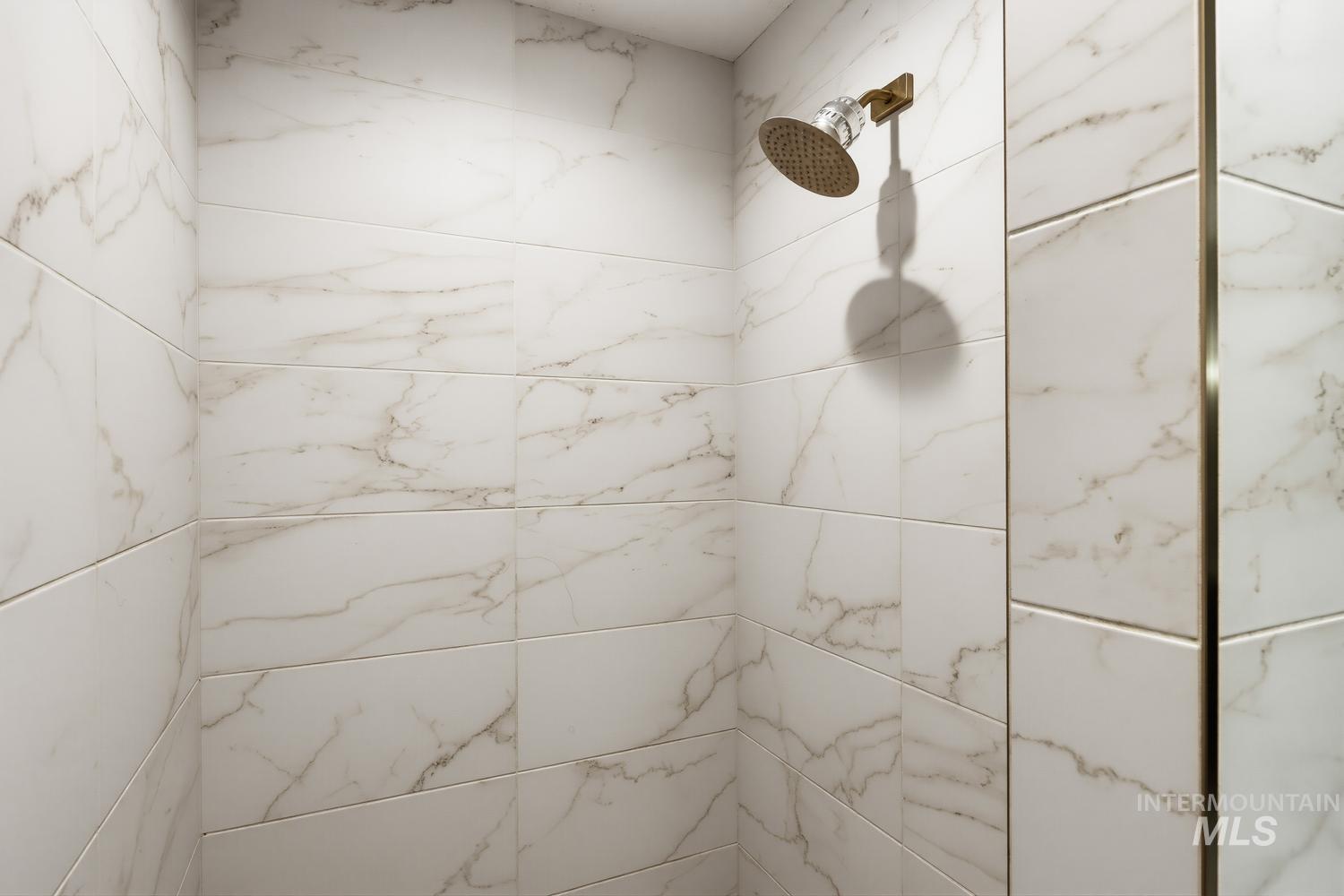 369 South Winthrop Way Boise, ID 83709 - Photo 30 of 50 Shower enclosure featuring large format white tile with subtle veining and a rain-style shower head with a brushed bronze finish