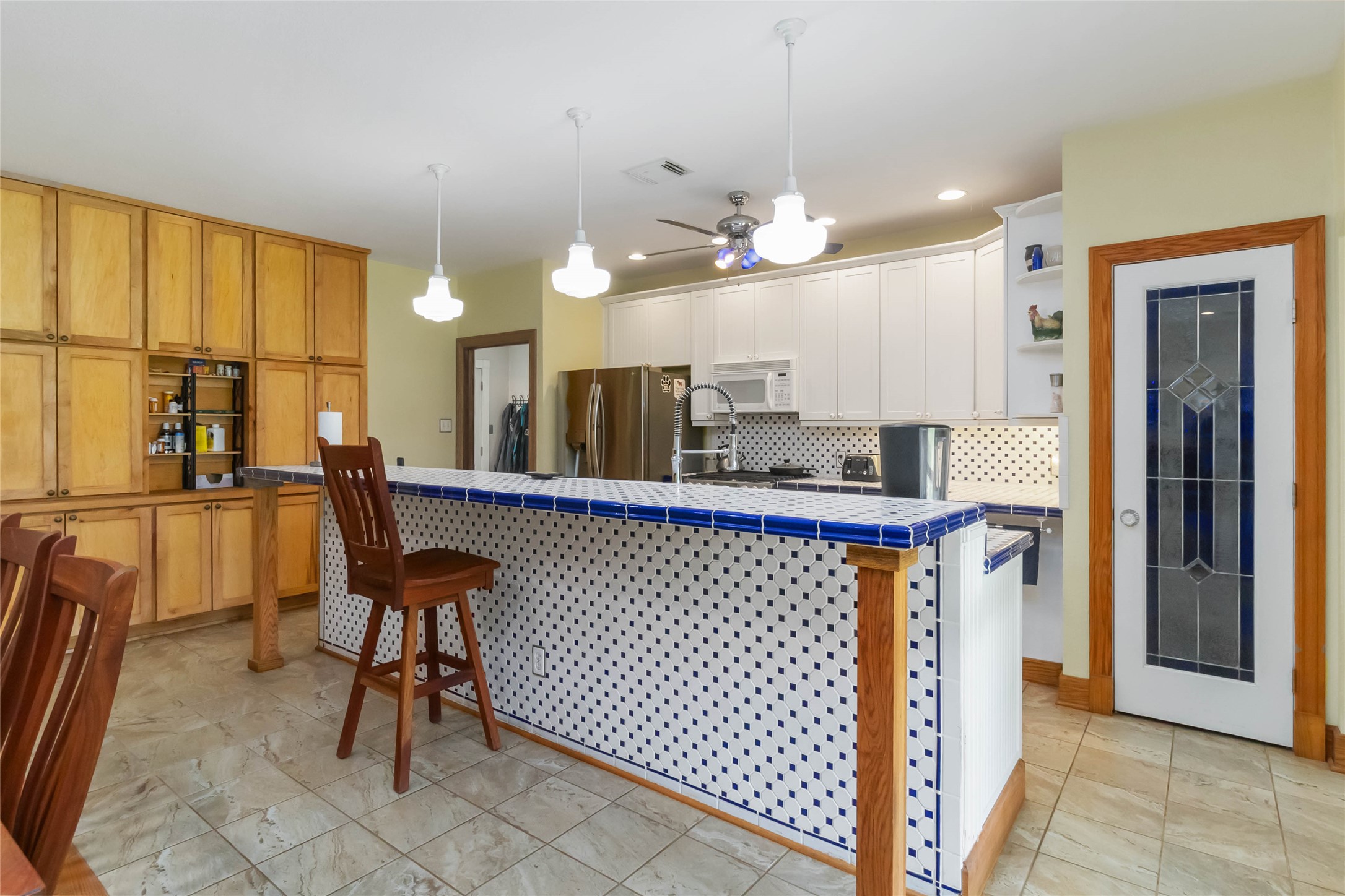 1208 Jeddo Road Rosanky, TX 78953 - Photo 7 of 40 A vibrant kitchen with a tiled breakfast bar and warm wooden cabinetry.