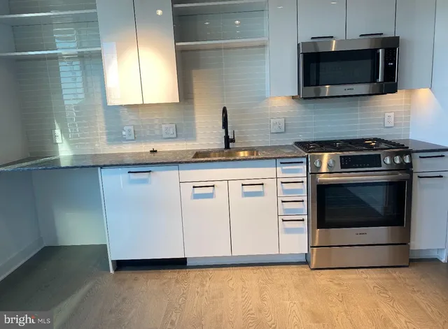 a kitchen with stainless steel appliances a stove microwave and sink
