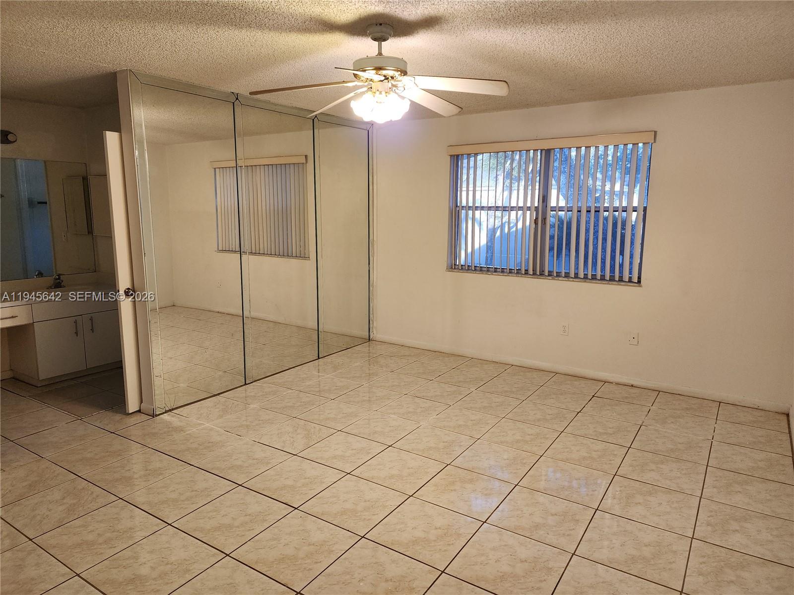 9863 Southwest 117th Place Miami, FL 33186 - Photo 14 of 29 a view of an empty room with window and chandelier fan