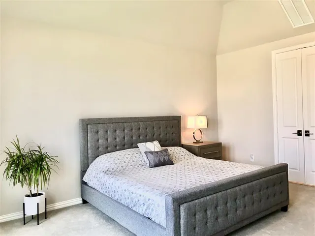 a bedroom with a bed and a potted plant on the dresser