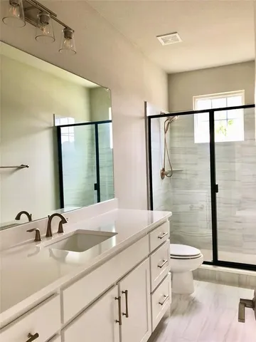 a bathroom with a granite countertop sink a toilet and shower