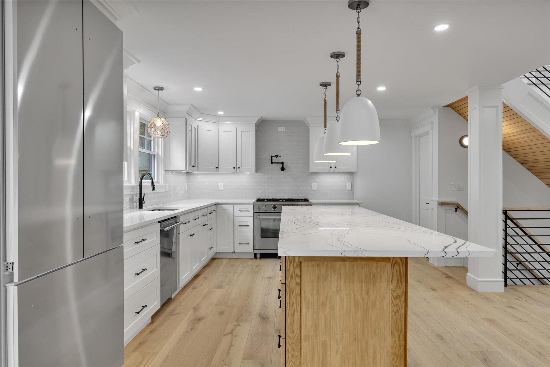 152 Pleasant Bay Road Harwich, MA 02645 - Photo 24 of 97 a large kitchen with kitchen island a stove a sink a refrigerator and white cabinets with wooden floor