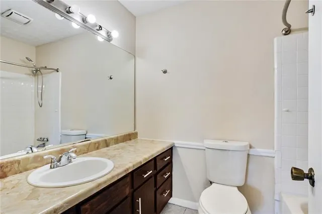 a bathroom with a granite countertop toilet sink and mirror