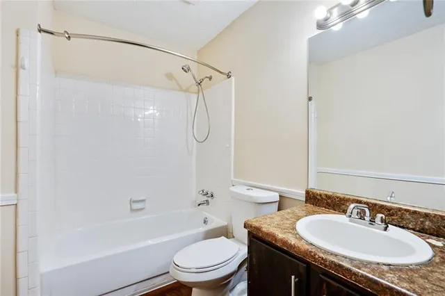 a bathroom with a granite countertop sink toilet mirror and shower