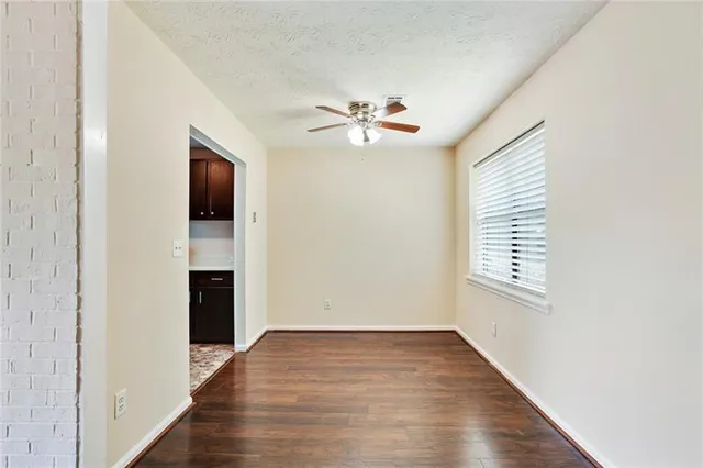 a view of an empty room with a window and a kitchen