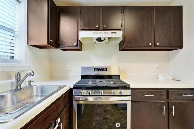 a kitchen with stainless steel appliances granite countertop wooden cabinets stove top oven and sink
