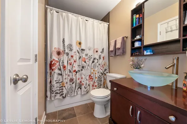 a bathroom with a granite countertop sink a toilet and a shower curtain