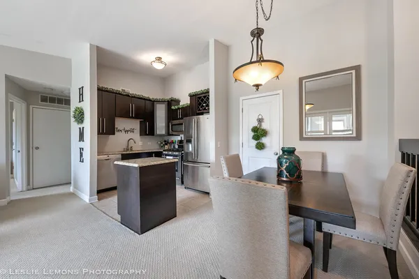 a kitchen with stainless steel appliances granite countertop a refrigerator a stove a sink dishwasher a dining table and chairs with wooden floor