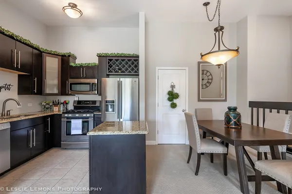 a kitchen with stainless steel appliances a dining table chairs a refrigerator and a stove