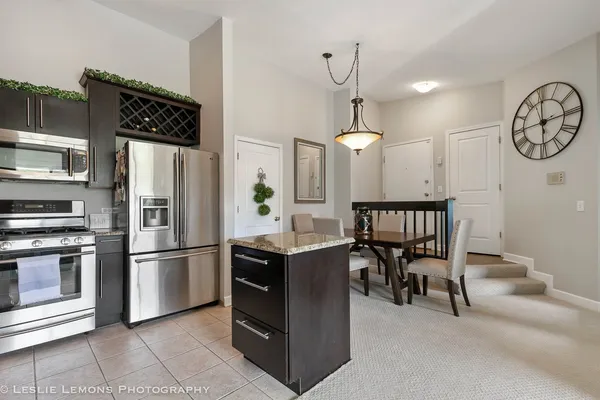 a kitchen with granite countertop a refrigerator a stove and a dining table