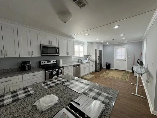 a kitchen with kitchen island granite countertop a sink appliances and cabinets