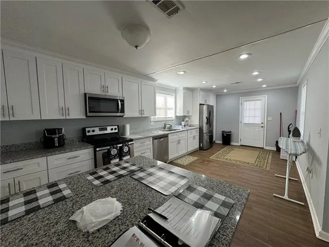 a kitchen with kitchen island granite countertop a sink appliances and cabinets