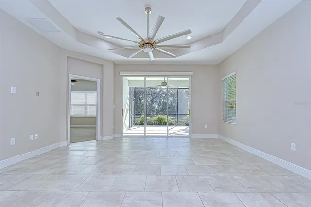 a view of an empty room with chandelier fan