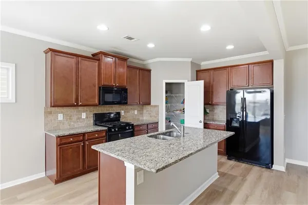 a kitchen with stainless steel appliances granite countertop a sink stove refrigerator and cabinets