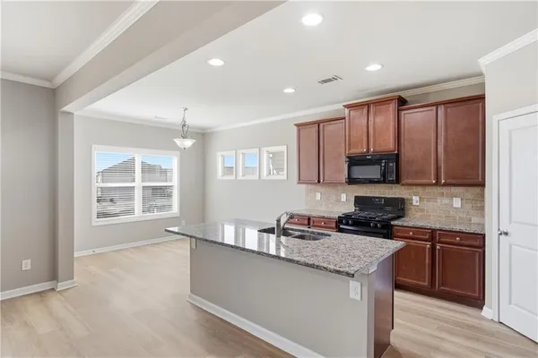 a kitchen with stainless steel appliances granite countertop a stove a sink and a microwave