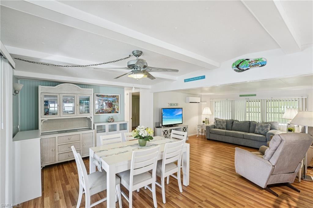 Dining area with a wall unit AC, beamed ceiling, wood finished floors, and ceiling fan