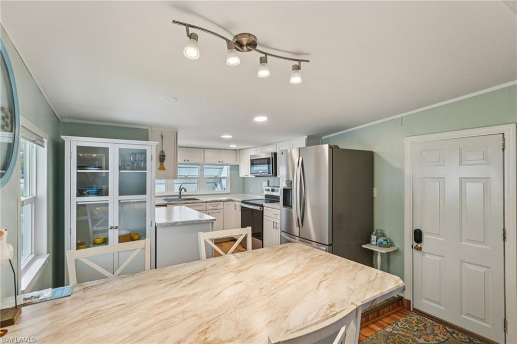 104 Willow Lane, Unit 30 Naples, FL 34114 - Photo 11 of 30 Kitchen with appliances with stainless steel finishes, ornamental molding, light countertops, wood finished floors, and white cabinetry