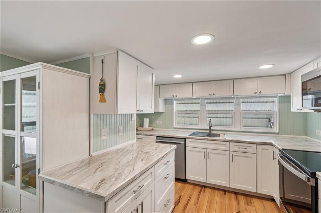 104 Willow Lane, Unit 30 Naples, FL 34114 - Photo 14 of 30 Kitchen featuring stainless steel dishwasher, electric range, white cabinetry, light wood-style flooring, and light stone counters