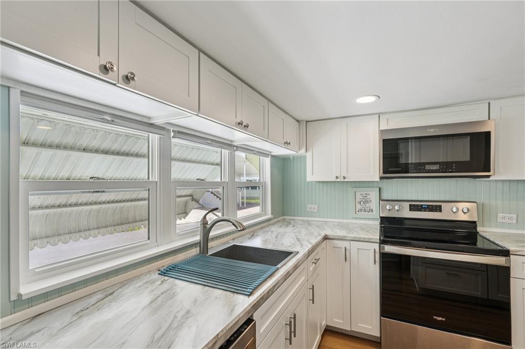 104 Willow Lane, Unit 30 Naples, FL 34114 - Photo 15 of 30 Kitchen with stainless steel appliances, white cabinets, and light stone countertops