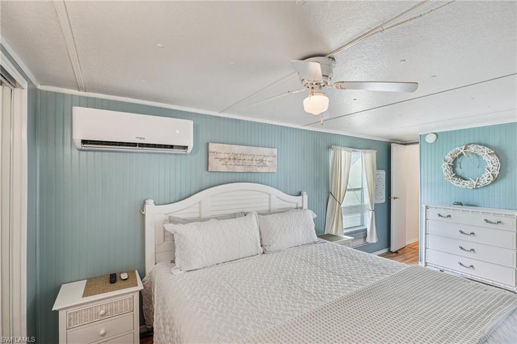 104 Willow Lane, Unit 30 Naples, FL 34114 - Photo 24 of 30 Bedroom with a wall unit AC, crown molding, ceiling fan, wood finished floors, and a textured ceiling