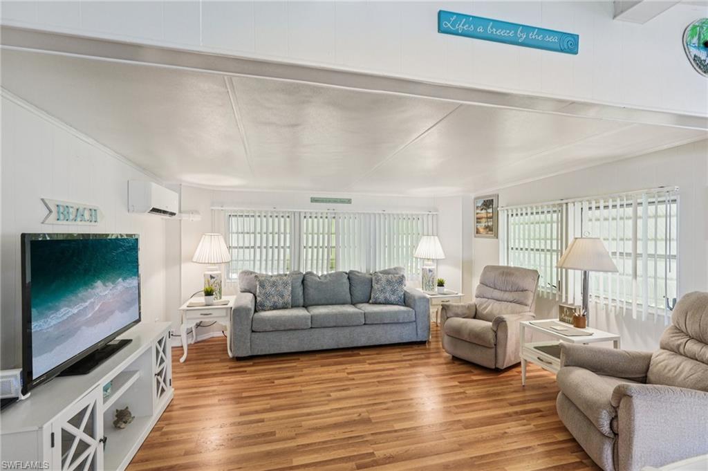 104 Willow Lane, Unit 30 Naples, FL 34114 - Photo 8 of 30 Living room featuring plenty of natural light, wood finished floors, and a wall unit AC