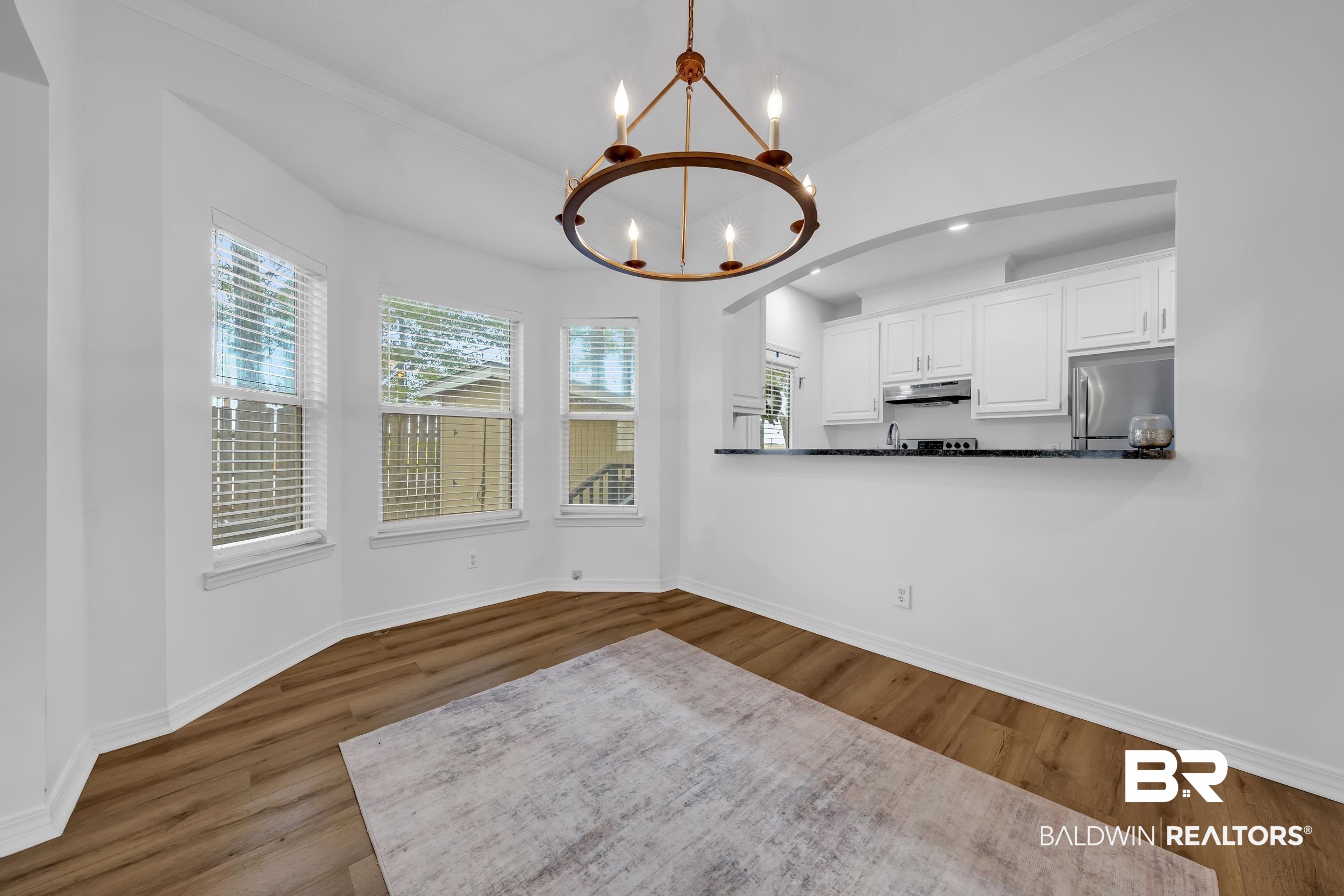 17488 Pandion Ridge, Unit A1 Fairhope, AL 36532 - Photo 8 of 18 Bright dining area featuring a prominent chandelier, wood-finish flooring, and multiple windows