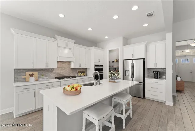a kitchen with a refrigerator a stove a sink and white cabinets
