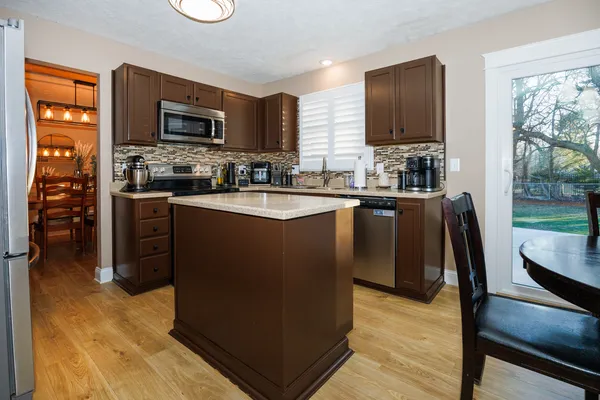 a kitchen with stainless steel appliances granite countertop a stove top oven a sink dishwasher a dining table and chairs with wooden floor