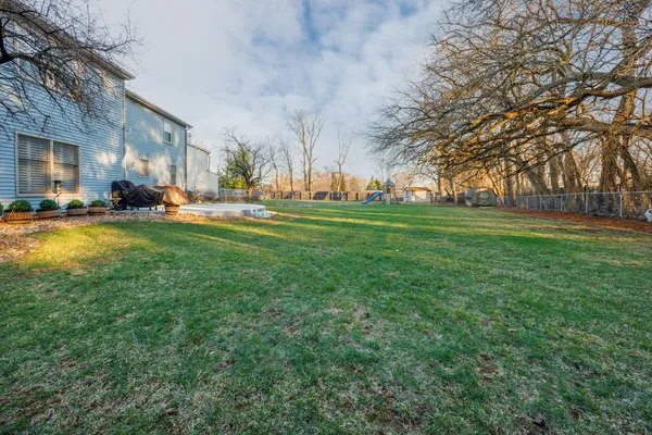 a view of a house with a big yard and large trees